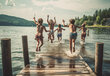 Fünf Kinder in Badehosen, die vom Steg in einen See springen