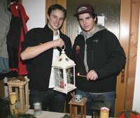 Manuel Bischofer und Patrick Unterer (beide von der Feuerwehrjugend) zünden mit dem Friedenslicht die Kerze in einer Laterne an. 